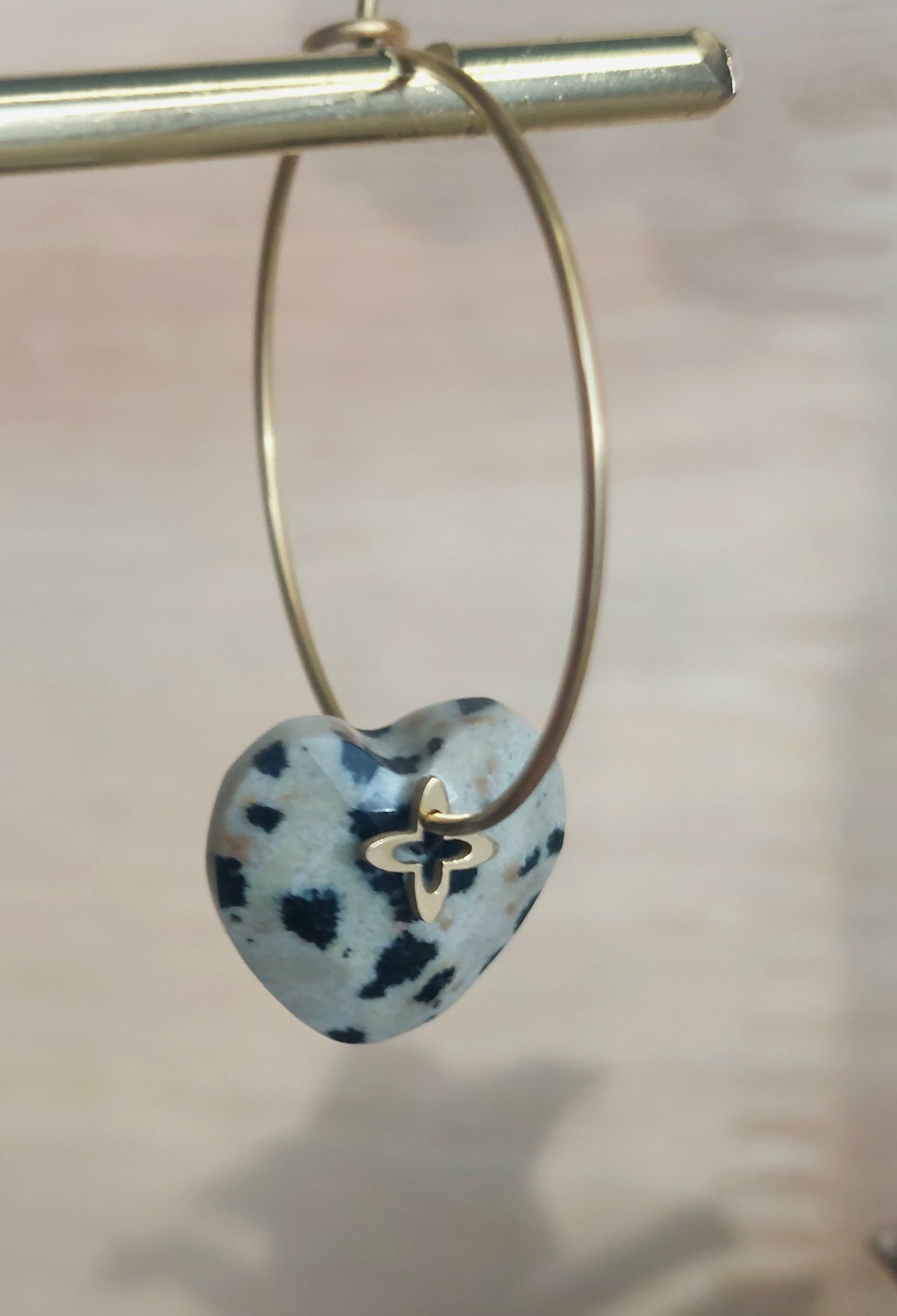 Zoom sur les créoles artisanales en jaspe dalmatien avec pampille trèfle dorée, mettant en valeur la texture et les reflets naturels.
