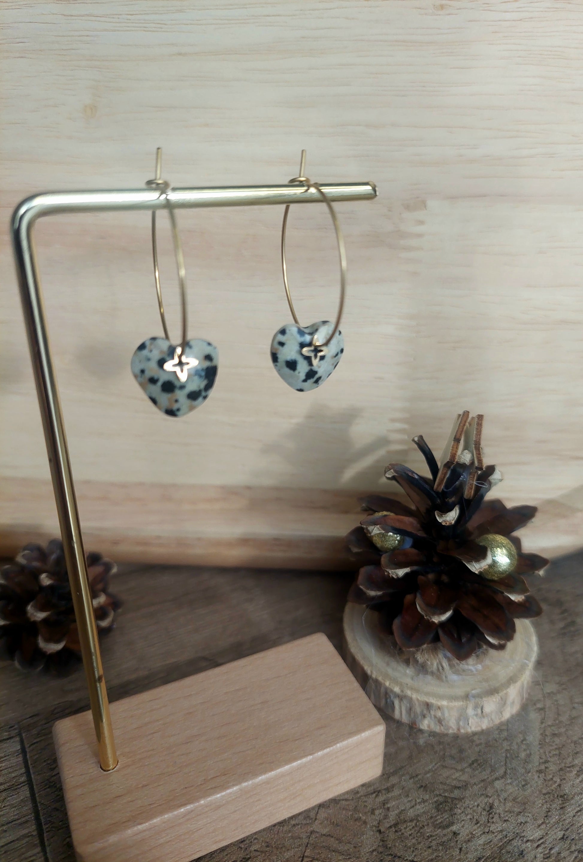 Créoles artisanales avec jaspe dalmatien et pampille trèfle dorée exposées sur un présentoir.