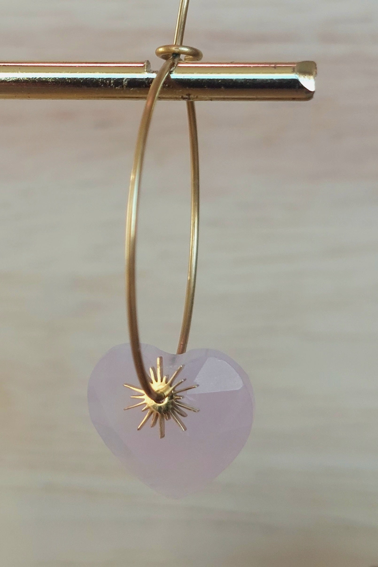 Zoom sur les créoles artisanales en quartz rose avec pampille soleil, mettant en valeur la couleur et les reflets naturels.
