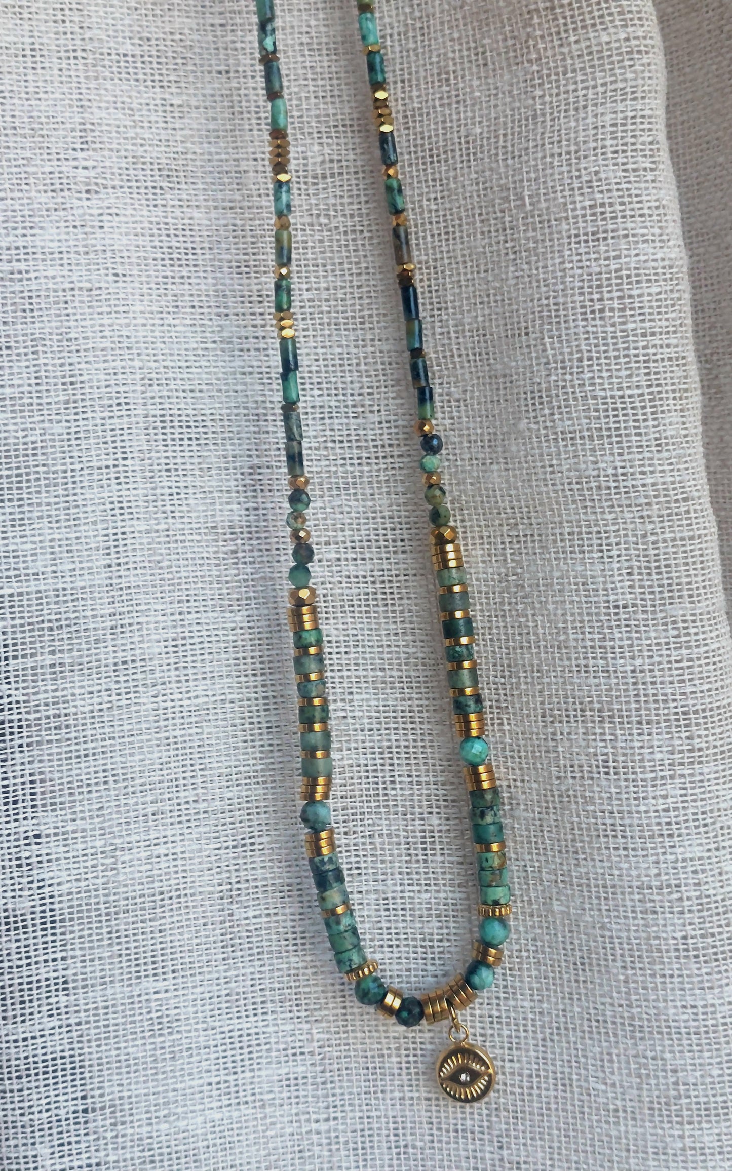Collier bohème en turquoise africaine, perles heishi et pendentif œil, présenté droit sur fond neutre