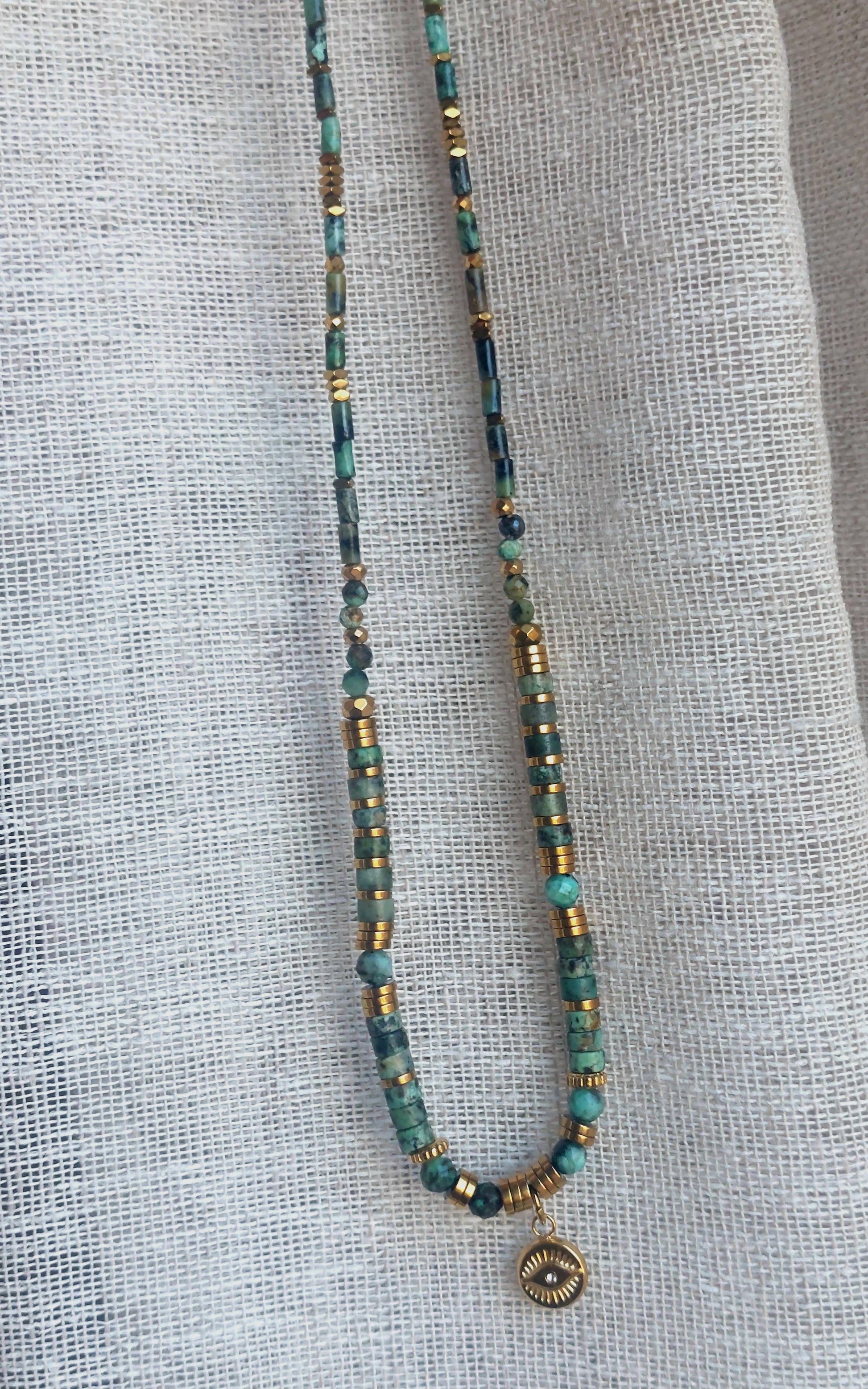 Collier bohème en turquoise africaine, perles heishi et pendentif œil, présenté droit sur fond neutre