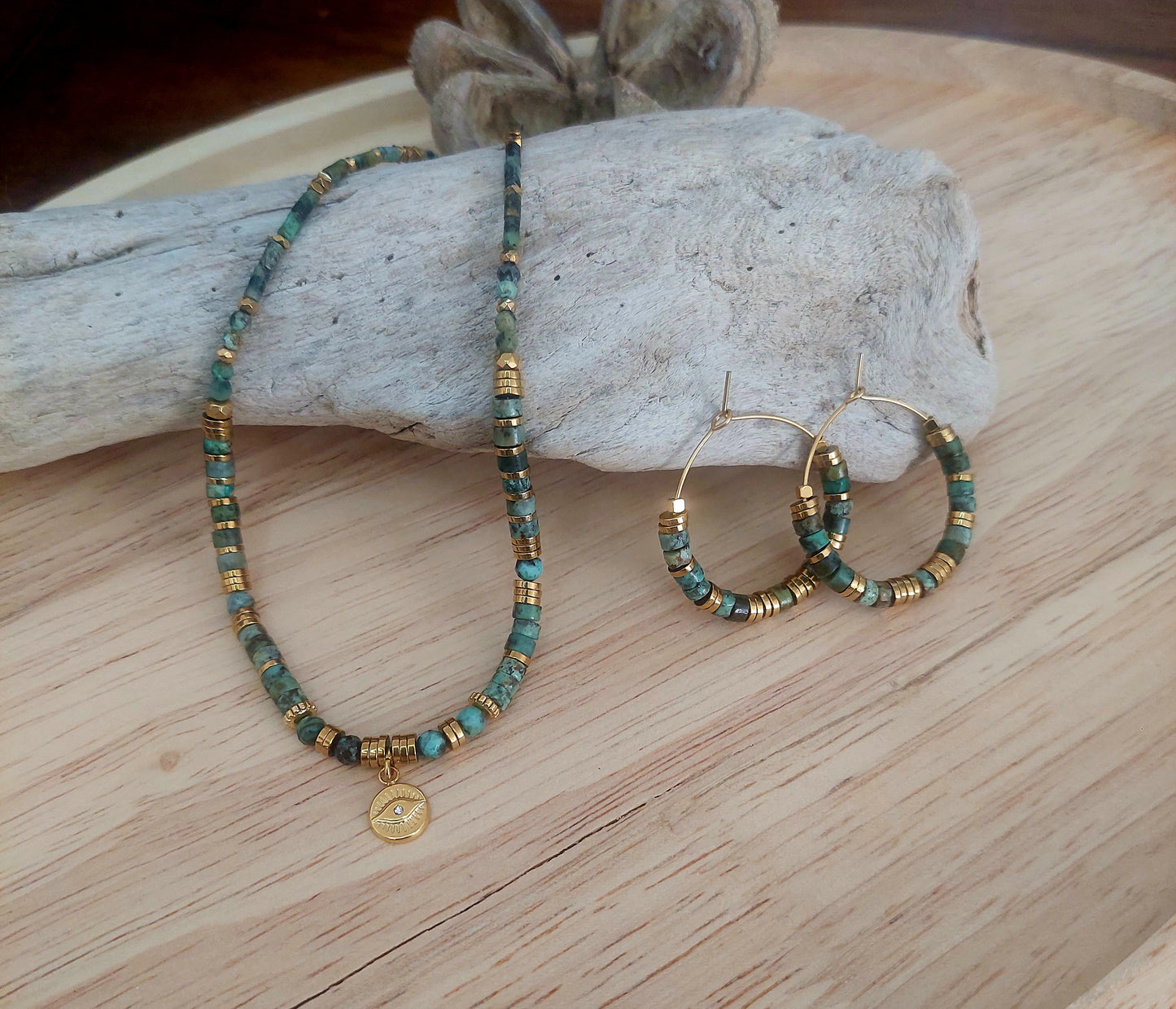Collier en perles heishi turquoises africaines et boucles d’oreilles assorties exposés sur un décor bohème, mettant en valeur un ensemble fait main, élégant et unique.