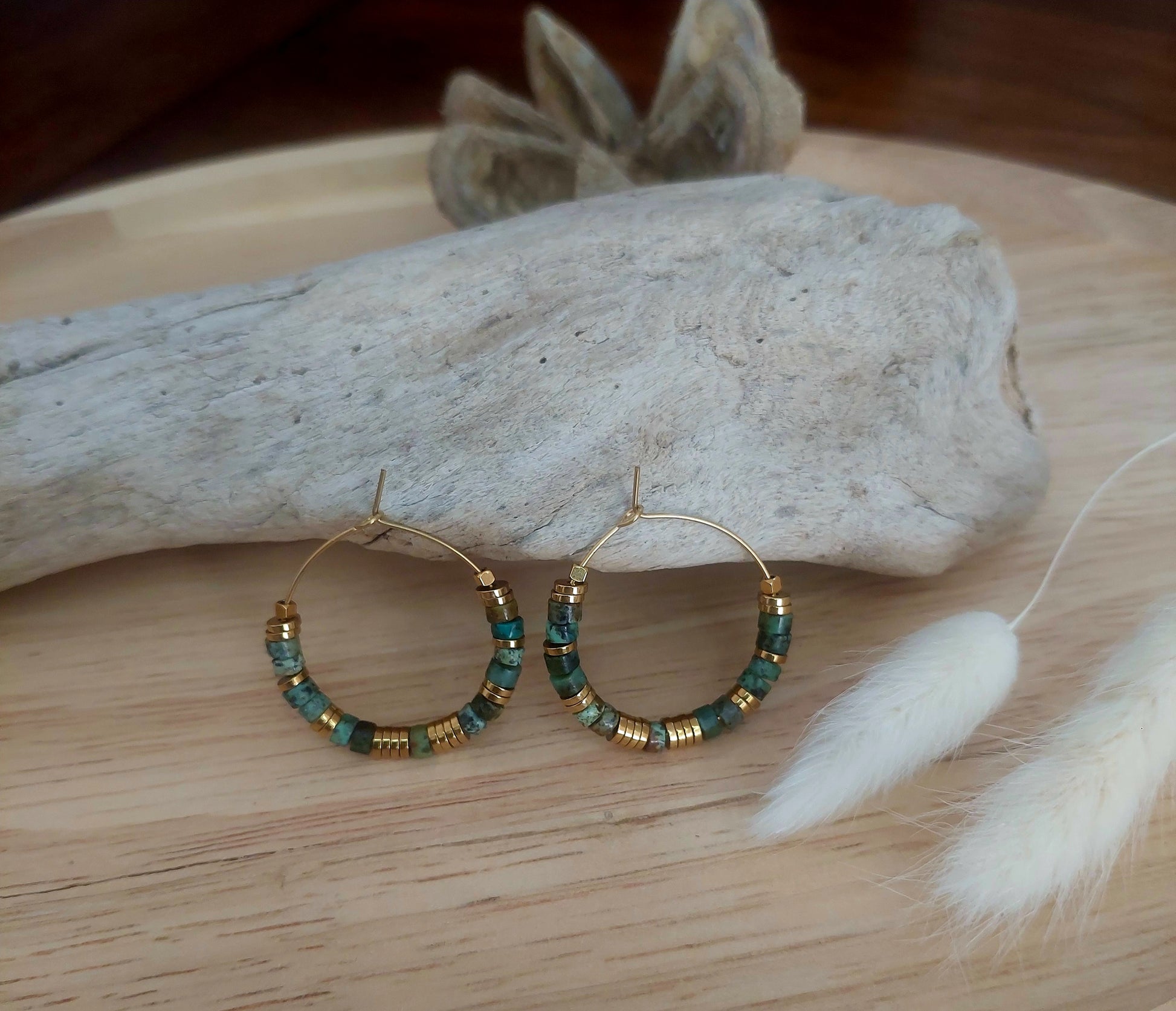 Boucles d’oreilles créoles en perles heishi turquoises africaines exposées en lumière neutre, mettant en valeur les détails du bijou bohème fait main, élégant et unique.