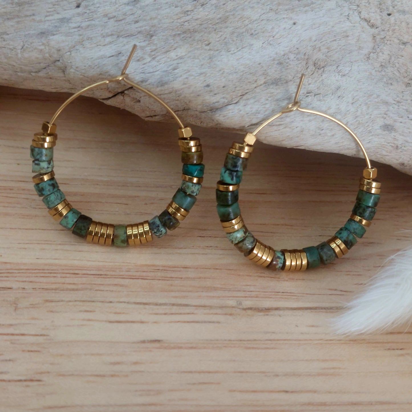 Boucles d’oreilles créoles en perles heishi turquoises africaines exposées sur un décor naturel, mettant en valeur un bijou bohème fait main, élégant et unique.