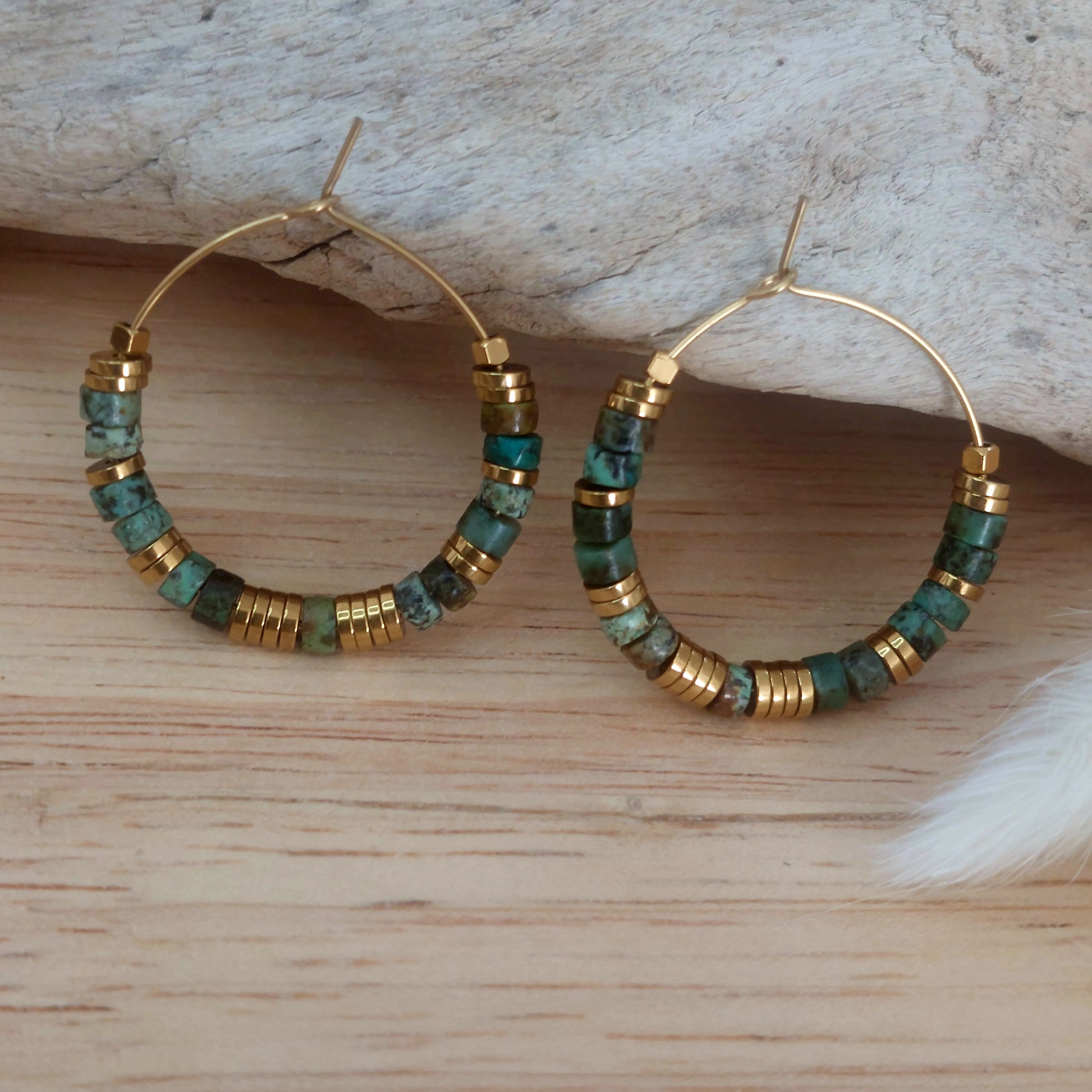 Boucles d’oreilles créoles en perles heishi turquoises africaines exposées sur un décor naturel, mettant en valeur un bijou bohème fait main, élégant et unique.