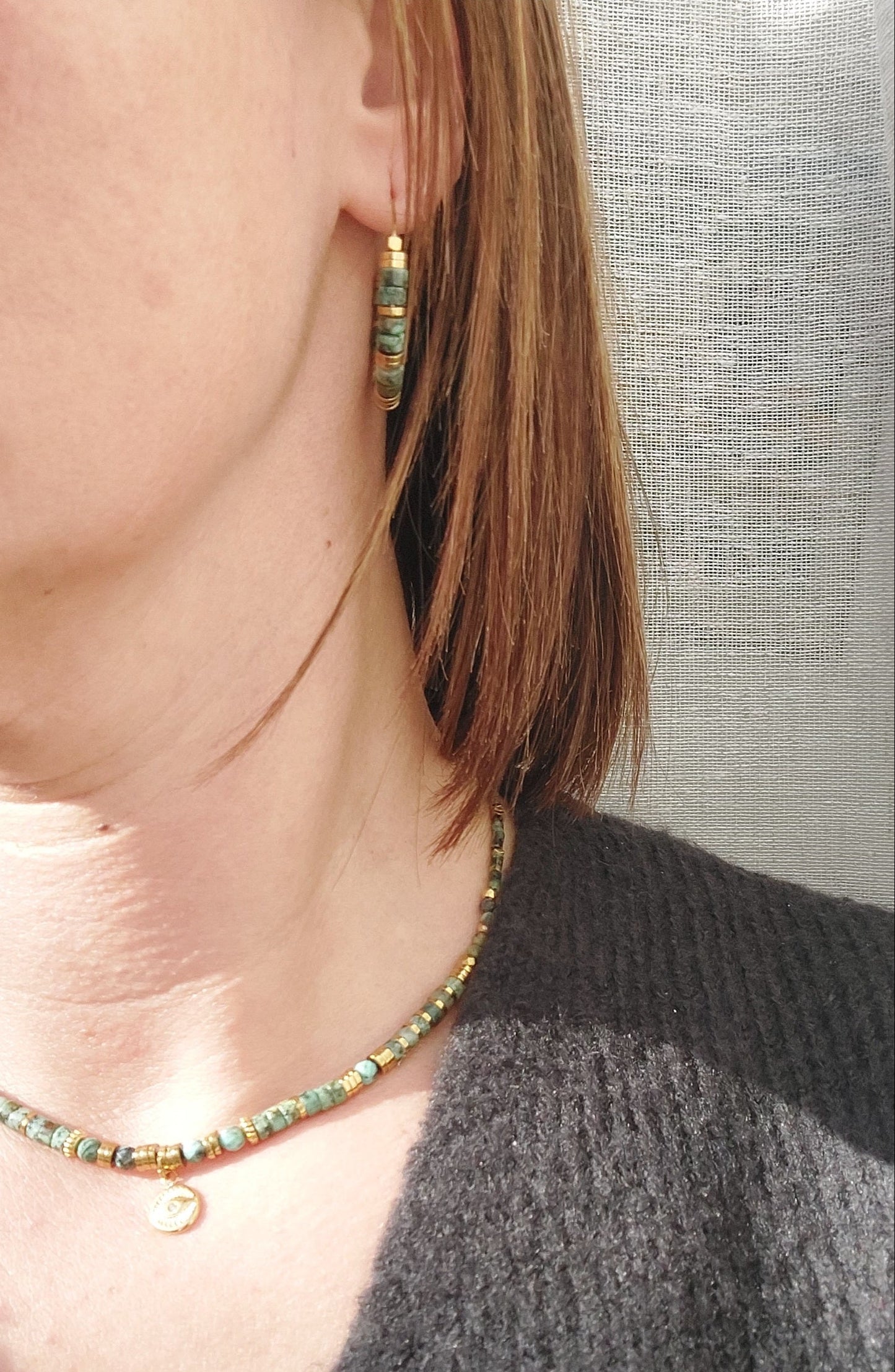 Boucles d’oreilles créoles en perles heishi turquoises africaines portées de face, mettant en valeur le bijou bohème fait main au design élégant et unique.