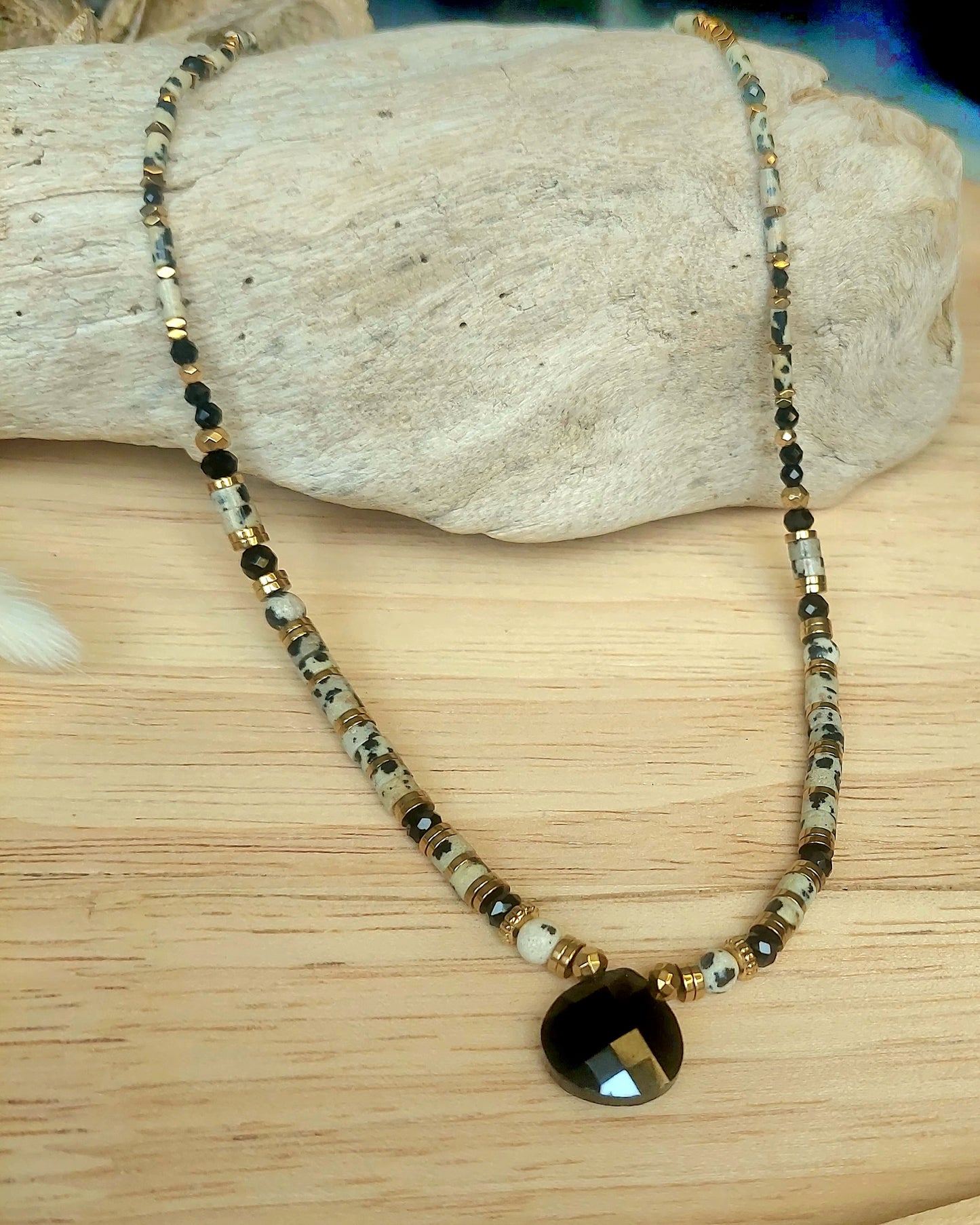 Collier jaspe dalmatien et agate noire exposé sur support naturel