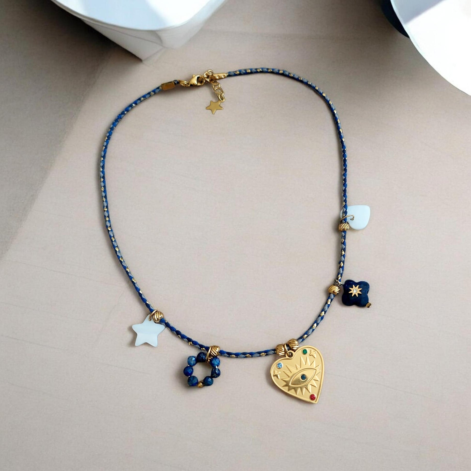 Collier bohème cordon bleu roi irisé doré  pendentif cœur en acier inoxydable, nacre et pendentifs lapis-lazuli exposé sur fond clair fait main