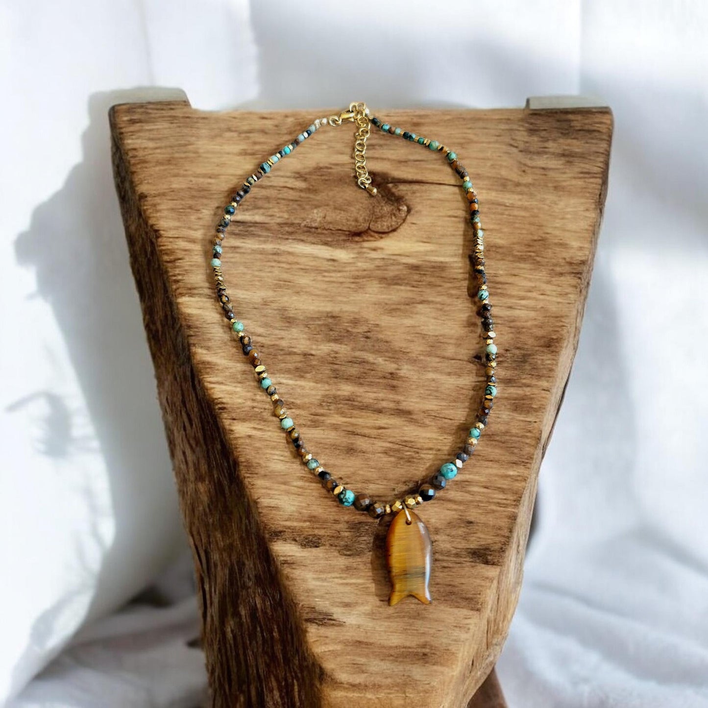 collier bohème perle naturelle fait main pendentif poisson œil de tigre posé sur présentoir