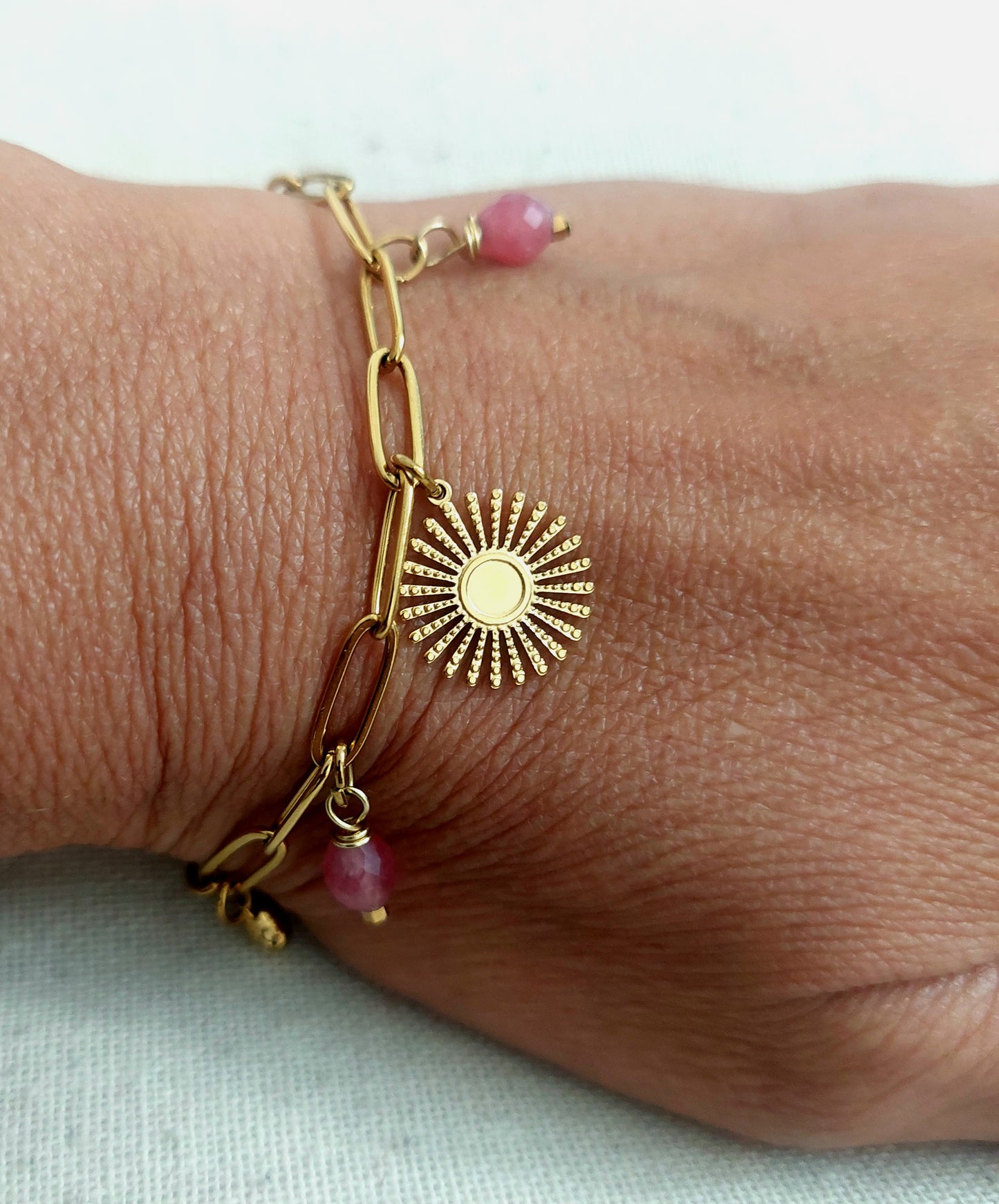 Gros plan bracelet femme en acier inoxydable porté, maille rectangle et pampilles naturelles quartz rose fraise