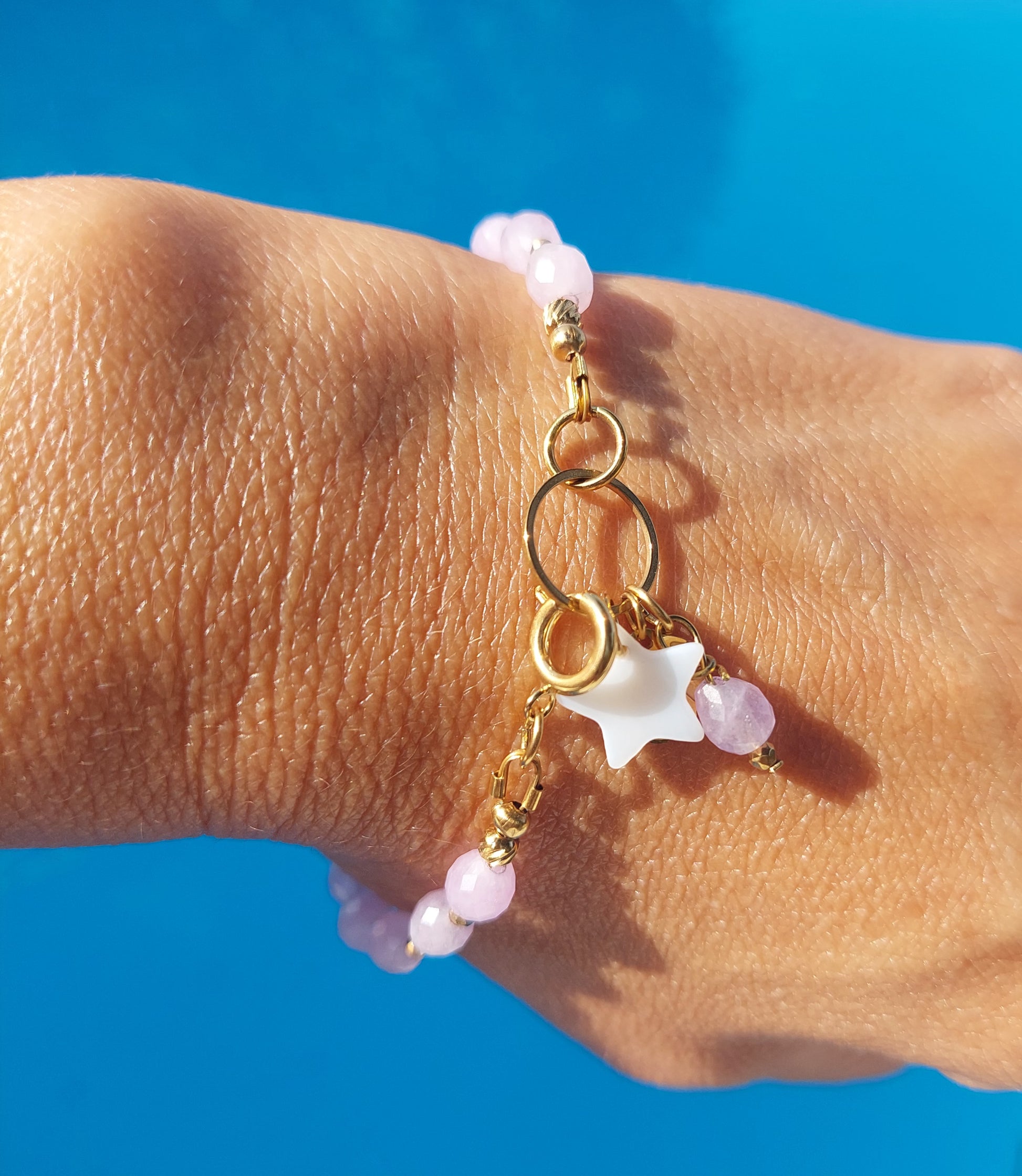 Détail du bracelet Alba en kunzite naturelle, étoile en nacre naturelle et acier inoxydable doré 316L porté au poignet