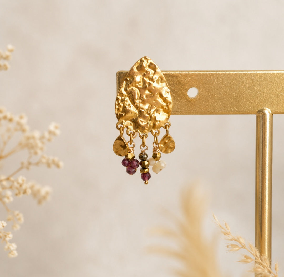 Gros plan des boucles clous d'oreilles martelées avec grenat et pyrites naturelles