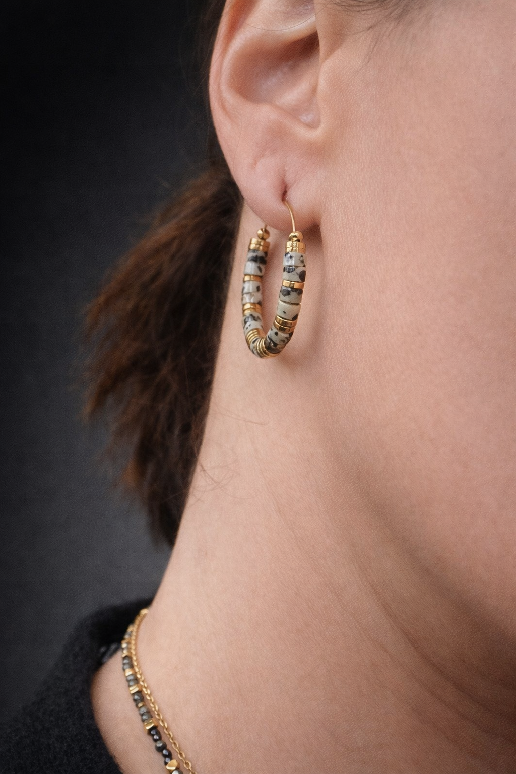 Boucles d’oreilles créoles en acier inoxydable avec perles en jaspe dalmatien naturel, bijou porté et présenté.