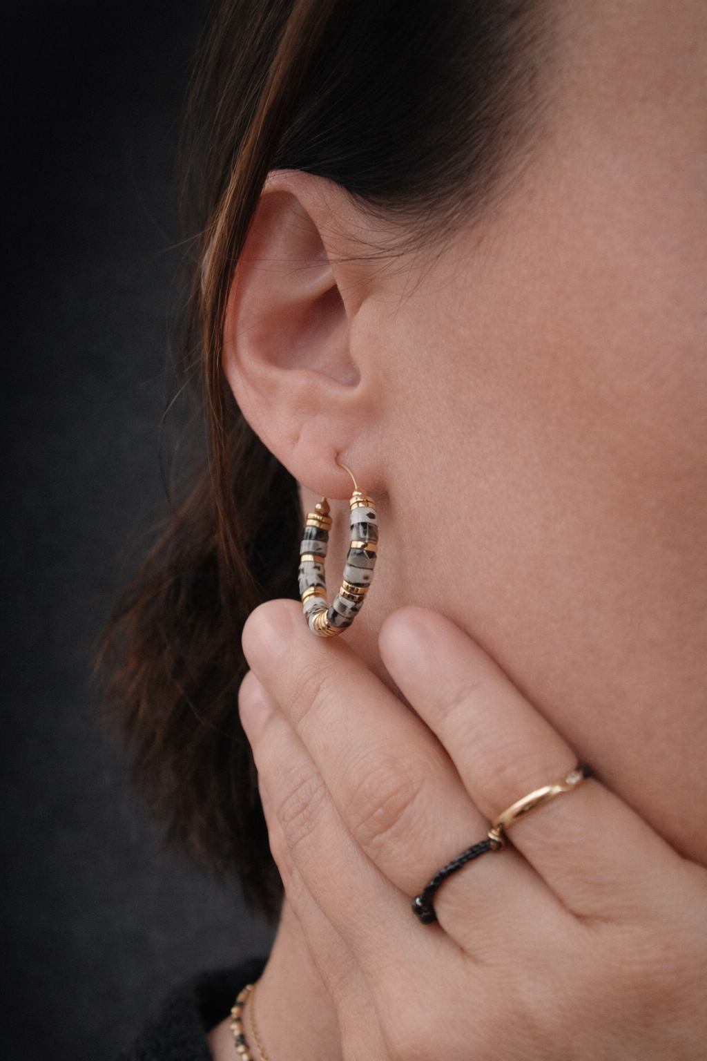 Créoles en acier inoxydable ornées de perles en jaspe dalmatien naturel, bijou porté à l’oreille et présenté en gros plan.