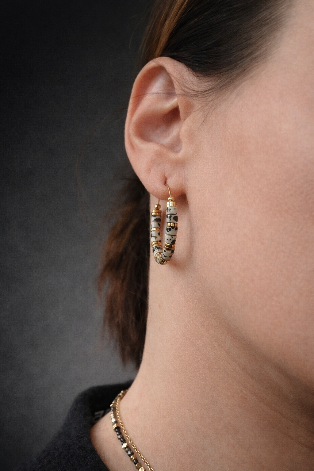 Boucles d’oreilles créoles en acier inoxydable et perles de jaspe dalmatien naturel, photo du bijou porté et produit exposé.