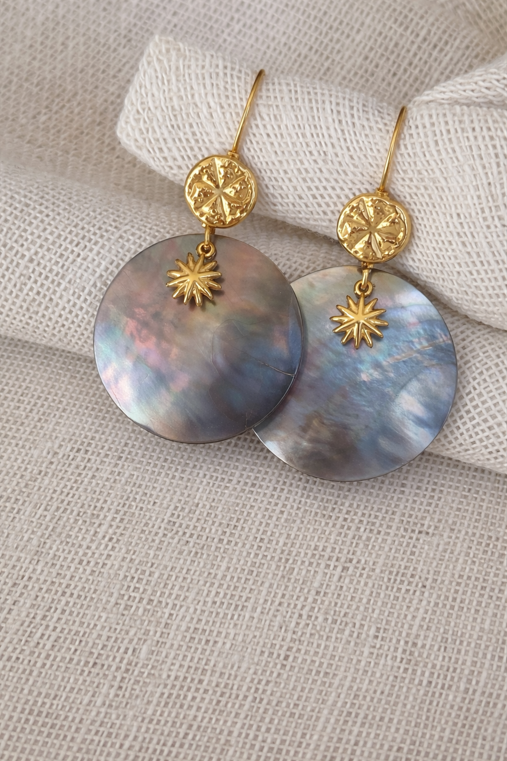 Boucles d’oreilles dormeuses bohèmes en acier inoxydable avec nacre naturelle et pendentif soleil sur fond clair bijou fait main